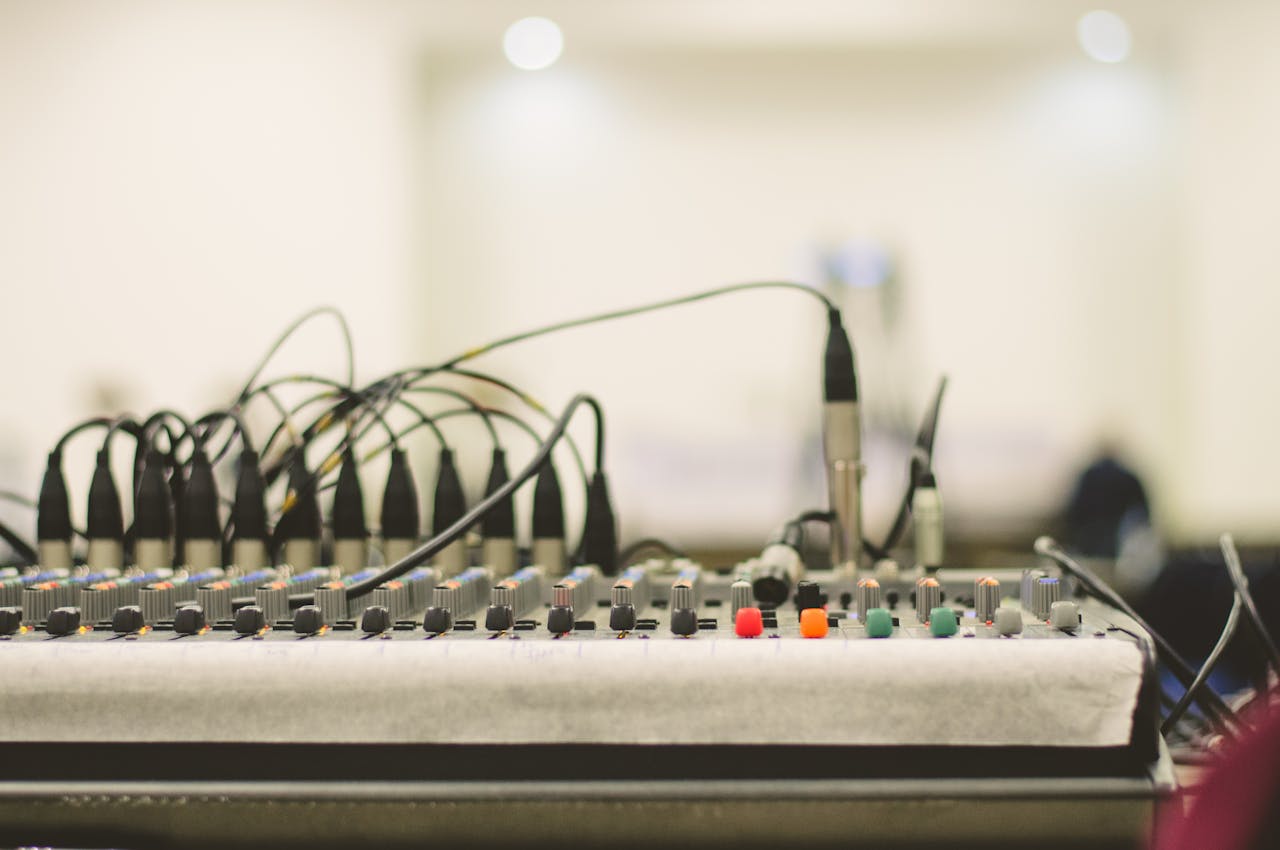 Detailed view of a professional audio mixing console with knobs, faders, and cables.